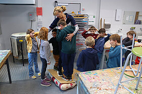 Gemeinsam getragen durch die Kraft der Luft: Katja Anstoetz und die Kinder des Pluskurses in der Grundschule Heidewald gemeinsam auf einer Decke voller Luftballons.