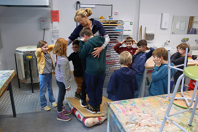 Gemeinsam getragen durch die Kraft der Luft: Katja Anstoetz und die Kinder des Pluskurses in der Grundschule Heidewald gemeinsam auf einer Decke voller Luftballons.