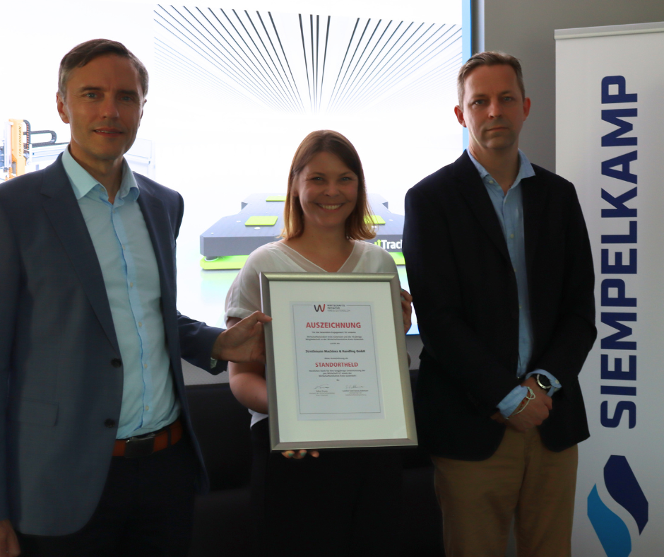 Die Geschäftsführer Torsten Ristow und Stefan Rehling (Siempelkamp Transport Systems GmbH) bekommen die Auszeichnung „Standortheld“ von Anna Niehaus (pro Wirtschaft GT) überreicht.