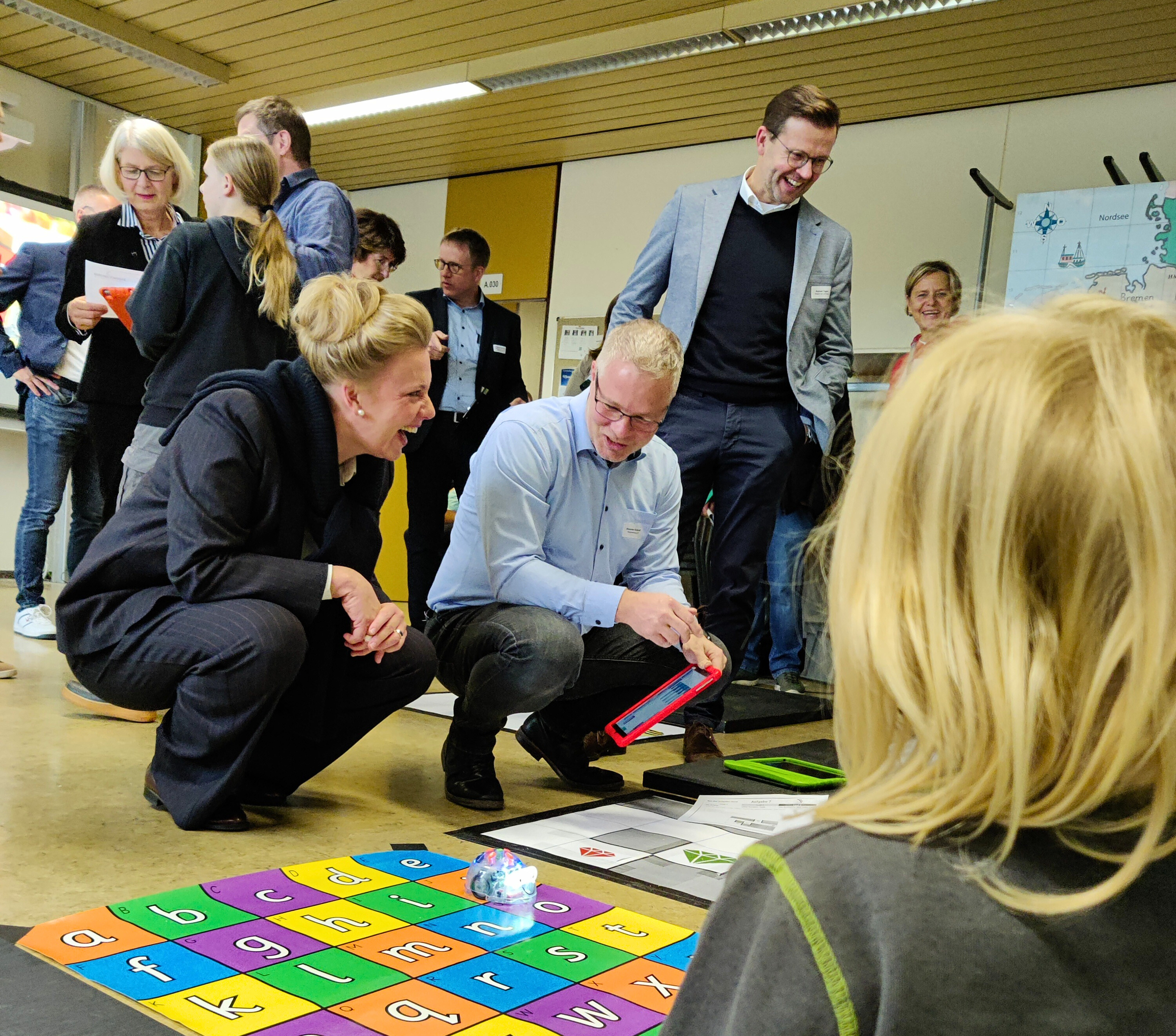 Ministerin Ina Brandes (links) bei einem Workshop der Medienberatung Kreis Gütersloh. Auch Landtagsabgeordneter Raphael Tigges (stehend, rechts) schaut den programmierenden Kindern über die Schulter.